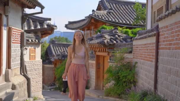 Young woman visits the busy touristic historical street Bukchon Hanok village in a center of Seoul, South Korea. Travel to Korea concept. Slowmotion shot — Stock Video