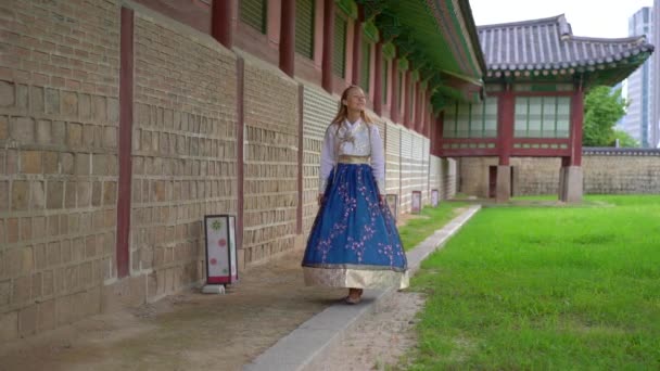 Jovem mulher vestindo vestido tradicional coreano Hanbok visitar palácio antigo em Seul, Coreia do Sul. Viajar para a Coreia conceito. Tiro em câmara lenta — Vídeo de Stock