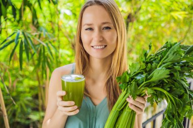 Young woman drinks Celery Juice, Healthy Drink, bunch of celery on a wooden background