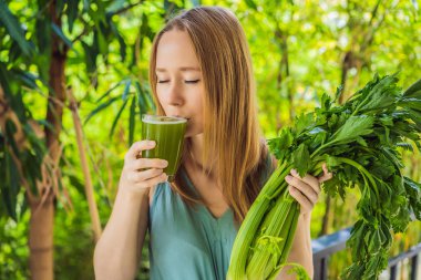Young woman drinks Celery Juice, Healthy Drink, bunch of celery on a wooden background
