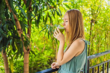 Young woman drinks Celery Juice, Healthy Drink, bunch of celery on a wooden background