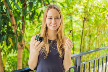 Young woman brush teeth using Activated charcoal powder for brushing and whitening teeth. Bamboo eco brush
