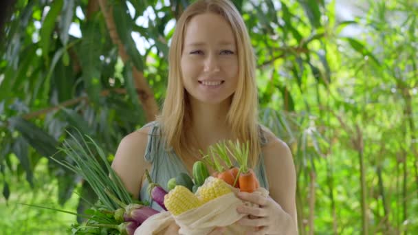 Young woman puts several kinds of vegetables in a reusable bag. Concept of reducing pollution by plastic. Reduce and reuse — Stock Video