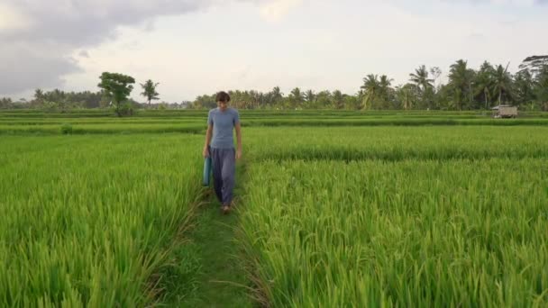 Un joven tiene un entrenamiento de yoga en un hermoso campo de arroz. Viajes a Asia concepto — Vídeo de stock