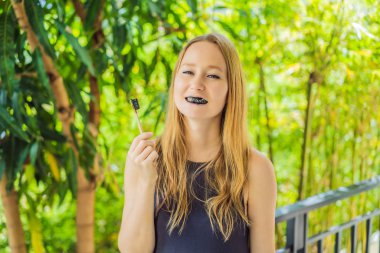 Young woman brush teeth using Activated charcoal powder for brushing and whitening teeth. Bamboo eco brush