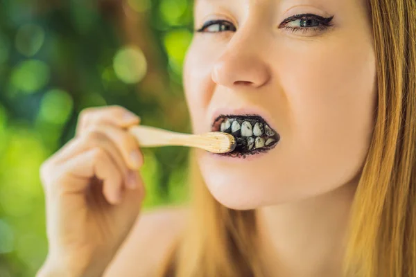 Jovem escovar os dentes usando carvão ativado em pó para escovar e clarear os dentes. Pincel ecológico de bambu — Fotografia de Stock