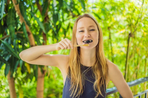 Young woman brush teeth using Activated charcoal powder for brushing and whitening teeth. Bamboo eco brush — Stock Photo, Image