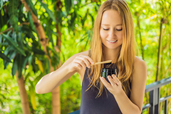Молодая женщина чистит зубы с помощью активированного угольного порошка для чистки и отбеливания зубов. Эко-кисть бамбука
