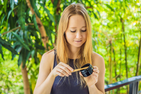 Молодая женщина чистит зубы с помощью активированного угольного порошка для чистки и отбеливания зубов. Эко-кисть бамбука
