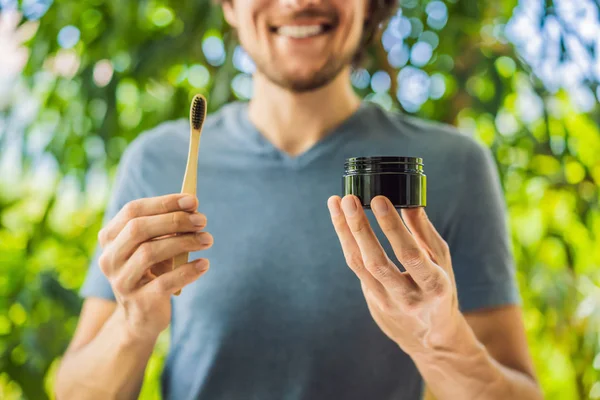 Jovem escovar os dentes usando carvão ativado em pó para escovar e clarear os dentes. Pincel ecológico de bambu — Fotografia de Stock