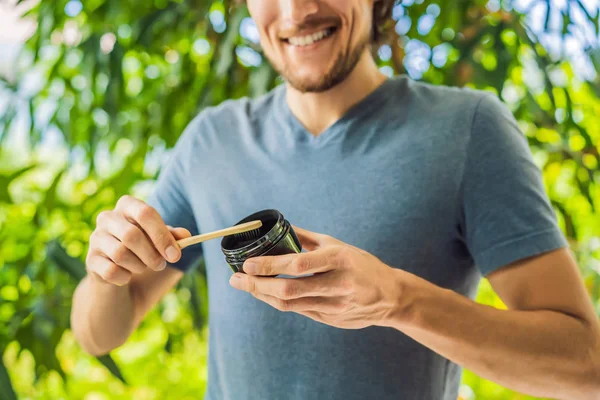 Young man brush teeth using Activated charcoal powder for brushing and whitening teeth. Bamboo eco brush — Stock Photo, Image