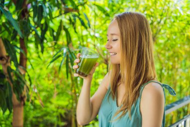 Young woman drinks Celery Juice, Healthy Drink, bunch of celery on a wooden background