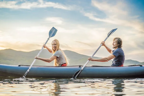 Férfiak és nők úszkálnak a kajakon a tengerben a sziget hátterében. Kayaking koncepció.Kayaking koncepció a család apa anya a tengeren — Stock Fotó