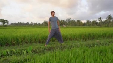 Genç bir adamın güzel bir pirinç tarlasında yoga eğitimi var. Asya 'ya seyahat. Yavaş çekim videosu