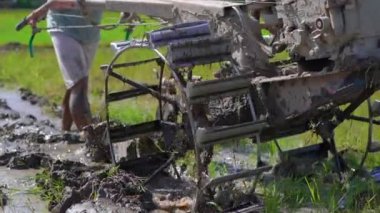 Güneydoğu Asya 'daki çiftçiler el traktörü kullanarak pirinç tarlası sürüyorlar. Asya 'ya seyahat. Yavaş çekim videosu