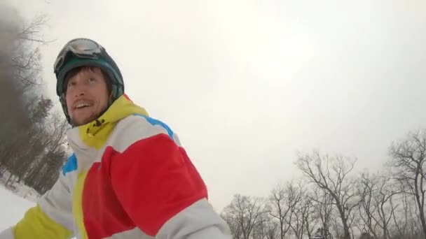 Um homem cavalga numa prancha de snowboard na pista de esqui. Conceito de recreação de inverno — Vídeo de Stock