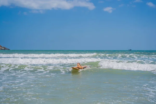Vacker ung kvinna rida våg. Sportig surfare kvinna surfa på bakgrunden av blå himmel, moln och transparenta vågor. Aktivt utomhus — Stockfoto