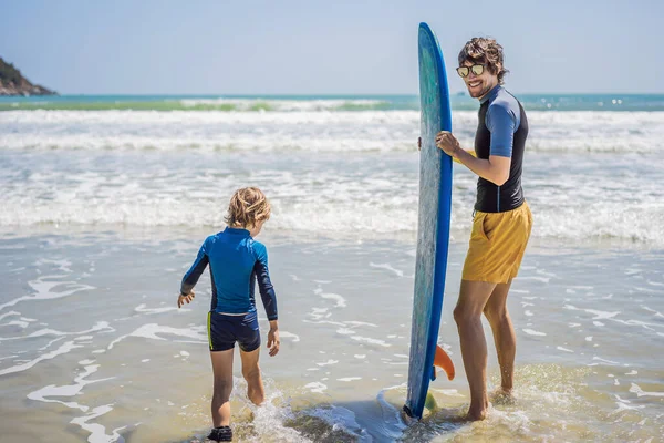 Apa vagy oktató tanítja a fiát szörfözni a tengerben nyaralás vagy nyaralás. Utazás és sport gyerekekkel koncepció. Szörflecke gyerekeknek — Stock Fotó