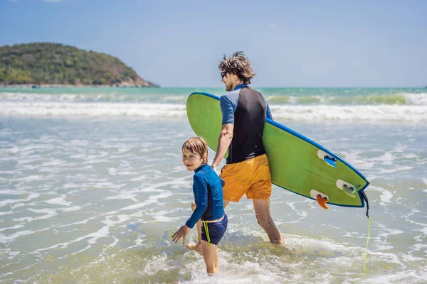 Отец или инструктор, обучающий своего сына серфингу в море во время отпуска или отпуска. Концепция путешествий и спорта с детьми. Урок серфинга для детей — стоковое фото