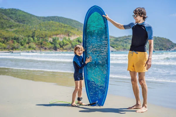 Otec nebo instruktor učí svého syna surfovat v moři na dovolené nebo na dovolené. Cestování a sport s dětským konceptem. Lekce surfování pro děti — Stock fotografie