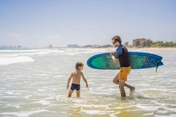 Padre o instructor enseñando a su hijo a surfear en el mar en vacaciones o vacaciones. Viajes y deportes con concepto infantil. Clases de surf para niños — Foto de Stock