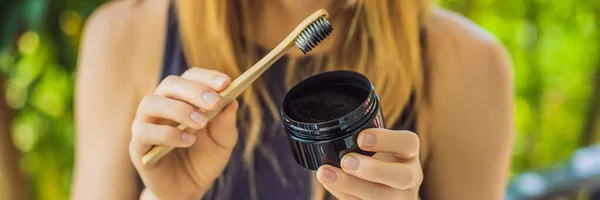 年轻妇女用活性炭粉刷牙，刷牙和美白。竹子生态刷横幅，长格式 — 图库照片