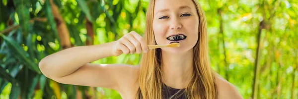 Jonge vrouw poetsen tanden met behulp van geactiveerde houtskool poeder voor het poetsen en bleken van tanden. Bamboe eco borstel Banner, Lang Formaat — Stockfoto