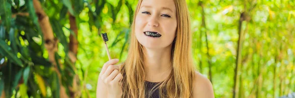 Νεαρή γυναίκα βουρτσίστε τα δόντια χρησιμοποιώντας ενεργοποιημένη σκόνη άνθρακα για το βούρτσισμα και λεύκανση δοντιών. Μπαμπού eco brush Banner, Long Format — Φωτογραφία Αρχείου