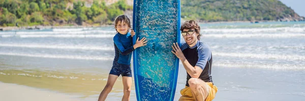 BANNER, LONG FORMAT Father or instructor teaching his son how to surf in the sea on vacation or holiday. Travel and sports with children concept. Surfing lesson for kids