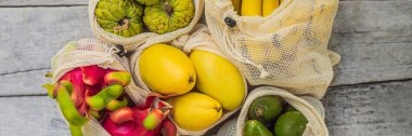 Banner, Long Format Fruit yeniden kullanılabilir bir çantada şık ahşap mutfak yüzeyinde. Sıfır atık kavramı, plastiksiz kavram. Sağlıklı beslenme ve detoks. Yaz meyveleri