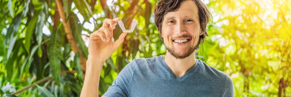 Man placing a bite plate in his mouth to protect his teeth at night from grinding caused by bruxism BANNER, LONG FORMAT — Stock Photo, Image