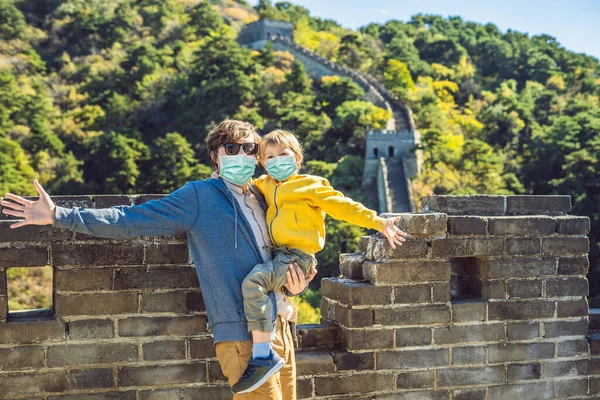 중국의 큰 벽에는 의료용 마스크를 쓴 관광객 아버지와 아들 이 있다. 중국 목적지. 중국에서는 어린이들 과 여행을 한다. 관광객들은 2019-ncov 바이러스를 두려워하고 있다. 의료용 마스크를 쓴 관광객 — 스톡 사진