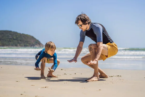 Padre o instructor enseñando a su hijo a surfear en el mar en vacaciones o vacaciones. Viajes y deportes con concepto infantil. Clases de surf para niños — Foto de Stock