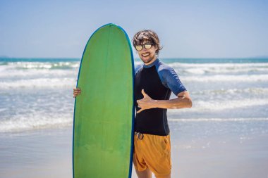 sörfçü bir sörf tahtası kumsalda holding