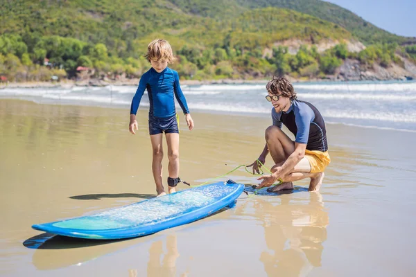 Far eller instruktör lär sin son hur man surfar i havet på semester eller semester. Resor och sport med barn koncept. Surfinglektion för barn — Stockfoto