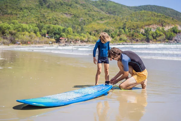 Vater oder Lehrer bringen seinem Sohn im Urlaub oder Urlaub das Surfen im Meer bei. Reisen und Sport mit Kindern. Surfstunde für Kinder — Stockfoto