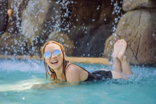 Young joyful woman under the water stream, pool, day spa, hot springs — Stock Photo, Image