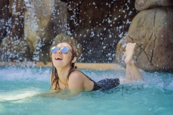 Junge fröhliche Frau unter dem Wasserstrom, Pool, Tagesbad, heiße Quellen — Stockfoto