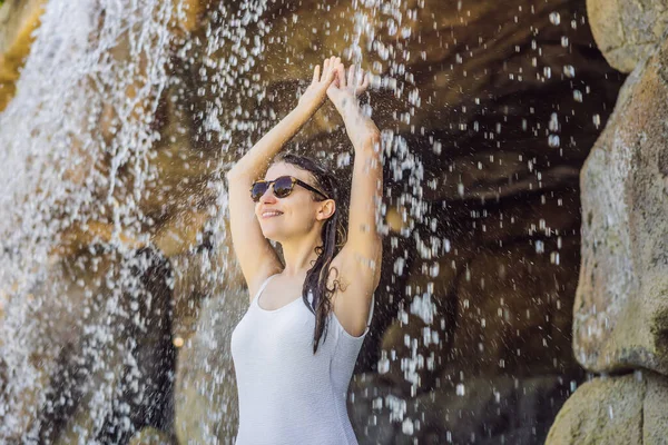Jonge vrolijke vrouw onder de waterstroom, zwembad, spa, warmwaterbronnen — Stockfoto