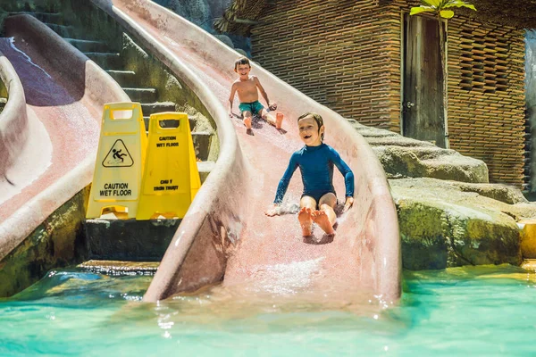 Kinder fahren auf einer Wasserrutsche in einem Wasserpark. Glückliche Kindheit — Stockfoto