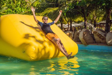 Adam havuzda şişme bir engelli parkurundan geçiyor.