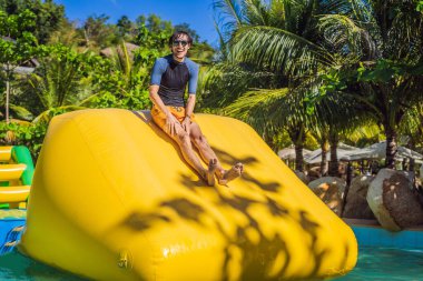 Adam havuzda şişme bir engelli parkurundan geçiyor.