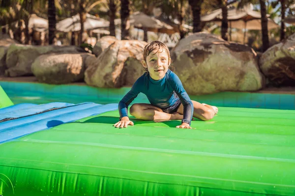 Garçon mignon court un parcours d'obstacles gonflable dans la piscine — Photo