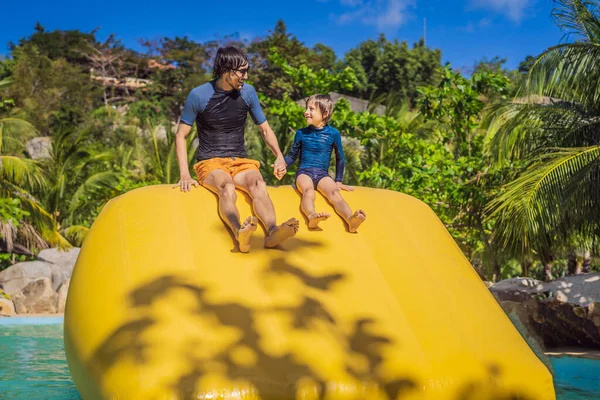 Papa et fils passent par un parcours d'obstacles gonflable dans la piscine — Photo