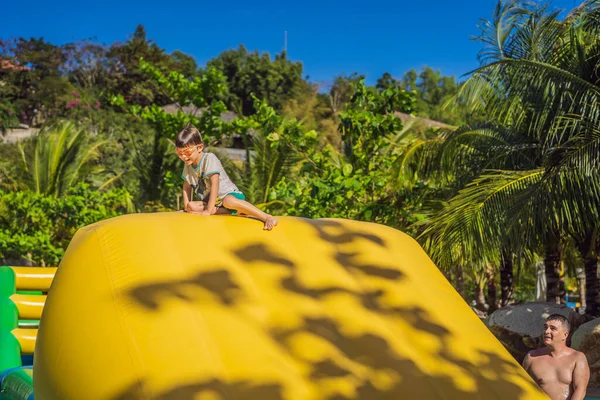 Papa et fils passent par un parcours d'obstacles gonflable dans la piscine — Photo