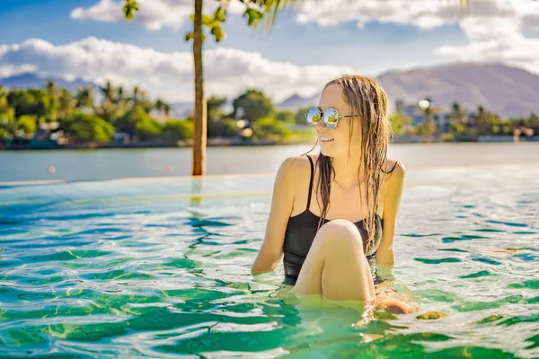 Piscina resort de lujo. Hermosa mujer turista relajarse en el retiro de vacaciones en vacaciones de verano. Bikini chica en traje de baño para tomar el sol disfrutando del fondo del océano —  Fotos de Stock