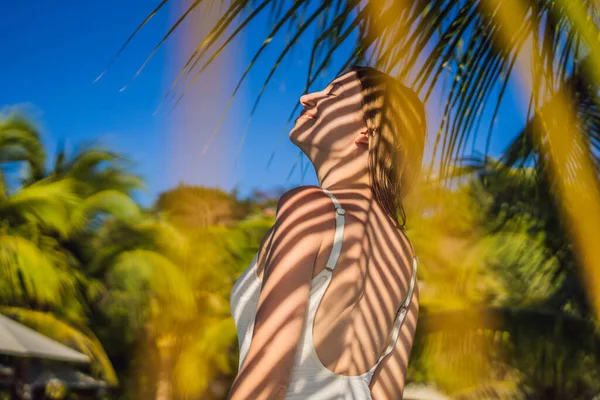 Giovane donna con l'ombra della foglia di palma sulla schiena. Rilassarsi sul mare — Foto Stock