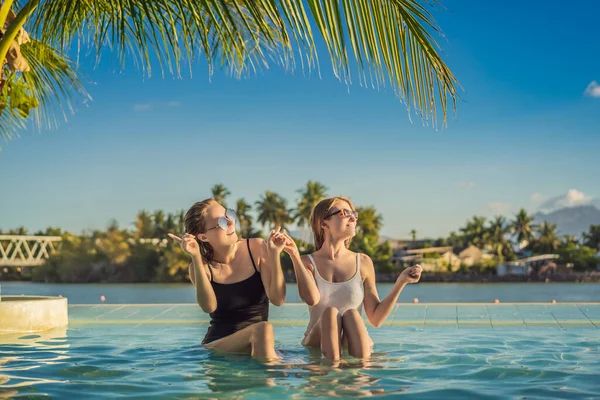 아름다운 두 젊은 여성 이 여름 방학 동안 리조트 수영장에 앉아 있습니다. 파티, 열 대 나라의 관광 — 스톡 사진