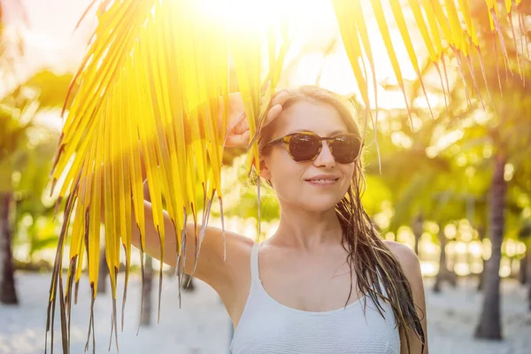 Joven hermosa mujer en traje de baño en la playa tropical, vacaciones de verano, hoja de palmera, piel bronceada, arena, sonriente, feliz. Mujer viajera feliz —  Fotos de Stock