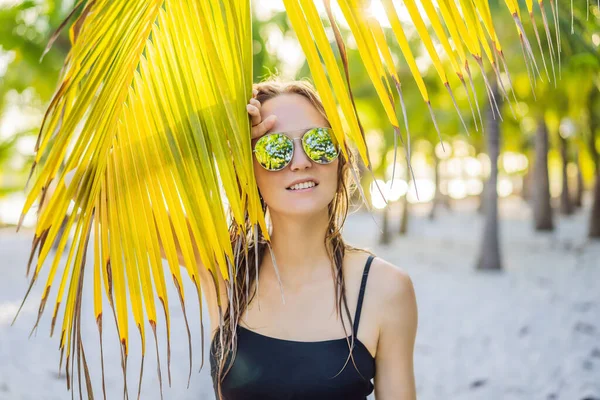 Giovane bella donna in costume da bagno sulla spiaggia tropicale, vacanza estiva, foglia di palma, pelle abbronzata, sabbia, sorridente, felice. Felice viaggiatore donna — Foto Stock